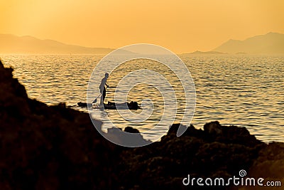 Silhouette of young couple on stand up paddle board. Active vacation, beach life Editorial Stock Photo