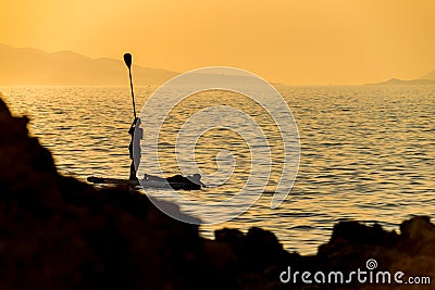 Silhouette of young couple on stand up paddle board. Active vacation, beach life Editorial Stock Photo