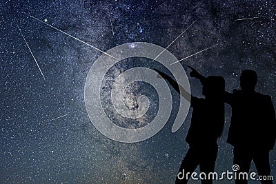 Silhouette of young couple watching Meteor Shower. Nigh Sky. Stock Photo