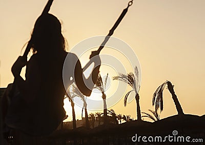 Silhouette of a young girl riding on a swing at sunset on a back Stock Photo