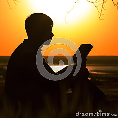 Silhouette of a young man with a Bible, male meditating and seeking answers in the Scriptures, the concept of religion and spiritu Stock Photo