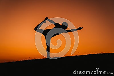 silhouette of young man in a park doing yoga sport. orange sky background. healthy lifestyle Stock Photo