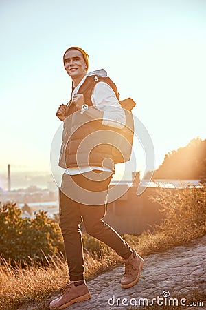 Young tourist blogger in orange hat walks. At backgroung is sunrise Stock Photo