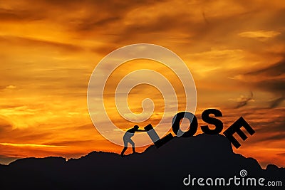 Silhouette of young man struggling to push a text of lose while climbing on the cliff , sky and sun light background. copy space Stock Photo