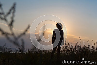 Silhouette of a young woman against the sky. Summer sunset Stock Photo