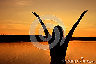 Silhouette of young woman over sunset sky and lake Stock Photo