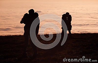 Silhouetted couples kissing above inversion fog Stock Photo