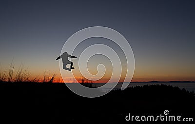 Silhouetted of man jumping in sunset Stock Photo