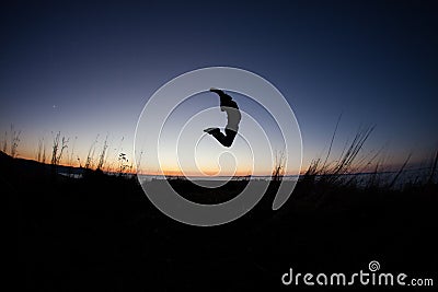 Silhouetted of man jumping in sunset Stock Photo