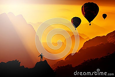 Silhouetted of man standing on mountain with hot-air balloons fl Stock Photo