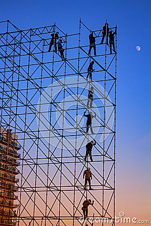 Silhouetted Men on metal stage scaffolding at dusk Stock Photo