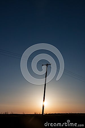 Silhouetted Power Pole On Canadian Prairie At Sunrise Vertical C Stock Photo