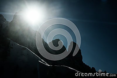 Silhouetted snow mountains slopes and peaks with sun rays and flares. Stock Photo