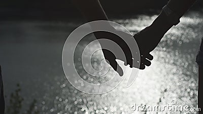 Silhouetten van gelukkige paarhanden die met rivierwaterspiegel bij achtergrond samenhouden stock footage Silhouetten van gelukkige paarhanden die met rivierwaterspiegel bij achtergrond samenhouden stock footage