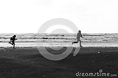 Silhouettes of a brother and a sister running wild and free at the beach Stock Photo