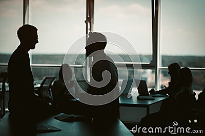 Silhouettes of business people have discussion in office interior with huge windows. Teamwork concept. Tinted image Stock Photo