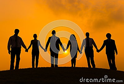 Silhouettes of Business People Holding Hands Outdoors Stock Photo