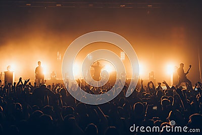 Silhouettes of concert crowd in front of bright stage lights. A sold out crowd on rock concert. Crowd of fans at music festive. Pa Editorial Stock Photo