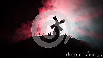 Silhouettes crowd of hungry zombies and old windmill on hill against dark foggy toned sky. Silhouettes of scary zombies walking at Stock Photo
