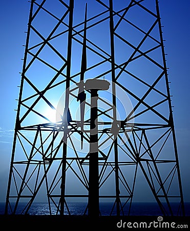Backlit electric tower and wind turbine Stock Photo
