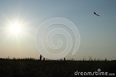 Silhouettes of a family father and children flying a kite Stock Photo
