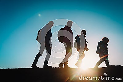 Silhouettes of family with two kids hiking in sunset mountains Stock Photo