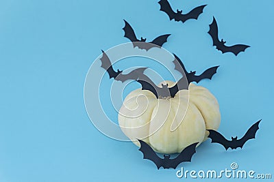 silhouettes of flying black paper bats next to a yellow pumpkin on a blue background. Stock Photo