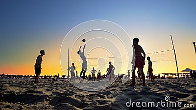 Silhouettes of a group of young people playing beach volleyball Editorial Stock Photo