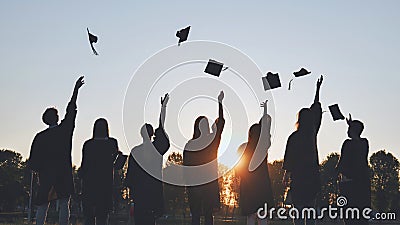 Silhouettes of Happy college graduates tossing their caps up at sunset. Stock Photo