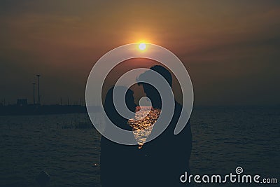 Silhouettes of hugging couple against the sea at sunset. Stock Photo