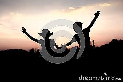 Silhouettes of kids jumping off a cliff at sunset Stock Photo