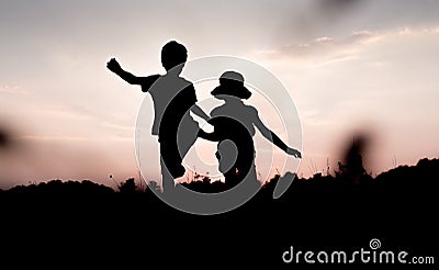 Silhouettes of kids jumping off a hill at sunset Stock Photo