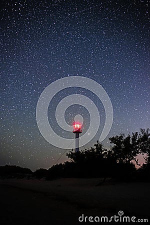 Silhouettes of the Lighthouse sandy beach and ocean against the background of the starry sky Stock Photo