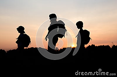 Silhouettes of mom hiking with her kids at sunset Stock Photo