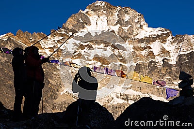 Silhouettes of Mountain Climbers pointing to high Peaks Stock Photo