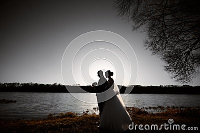 Silhouettes of newlyweds on the background of the river and the setting sun Editorial Stock Photo