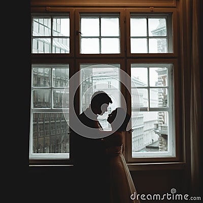 Silhouettes of newlyweds standing in the front of a bright window Stock Photo