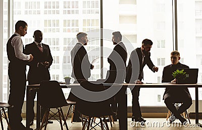 Silhouettes of people against the window. A team of young businessmen working and communicating together in an office Stock Photo