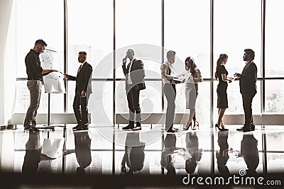 Silhouettes of people against the window. A team of young businessmen working and communicating together in an office Stock Photo