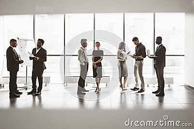 Silhouettes of people against the window. A team of young businessmen working and communicating together in an office Stock Photo