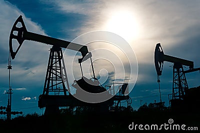 Silhouettes of pumpjacks on an oil wells against the background of an alarming sky Stock Photo