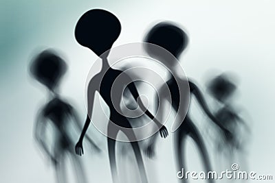 Silhouettes of spooky aliens and bright light on behind them Stock Photo