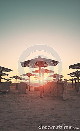 Silhouettes of sun umbrellas and windscreens on a beach at sunset, color toning applied Stock Photo