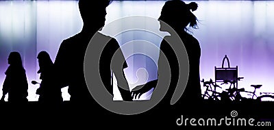 Silhouettes of teen boy and girl standing in front of modern multupurpose building, in the night Stock Photo