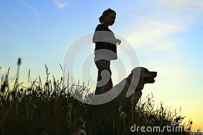 Silhouettes Of A Teenage Girl Walking With Her Pet. Stock Photo