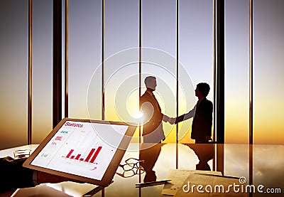 Silhouettes Of Two Businessmen Shaking Hands Together In A Board Room Stock Photo