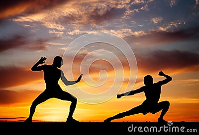 Silhouettes of two fighters on sunset background Stock Photo