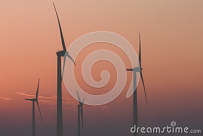 Silhouettes of wind turbines against the sunset . Stock Photo