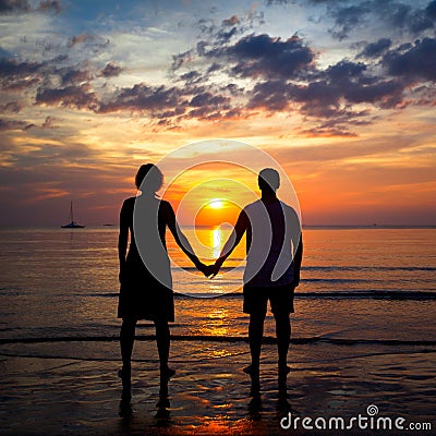 Silhouettes young couple on the beach at sunset Stock Photo