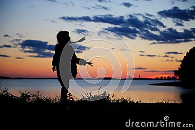 Silhouhette of a child girl walking in the sunset Stock Photo